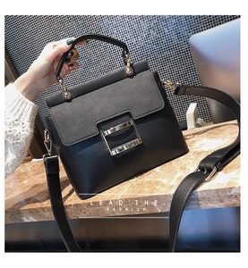Detail of black crossbody bag featuring matte flap, gold square buckle and wide strap