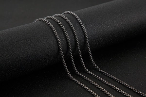 Close-up of black stainless steel O-chain link necklace on dark cylindrical display stand