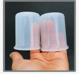 Detail of 100ml translucent silicone measuring cup with clear scale held by hand