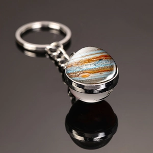 Macro shot of Jupiter pattern glass dome keychain with metal ring on reflective surface