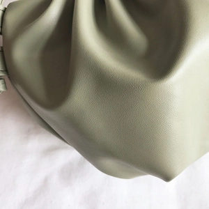 Green leather dumpling bag with soft pleats and pebbled texture on white fabric