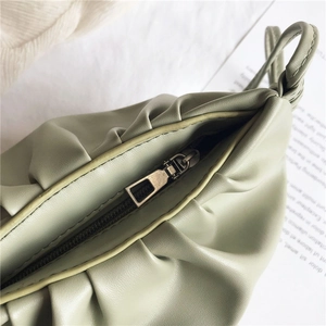 Detail of light green pleated handbag showing premium golden zipper and soft leather texture
