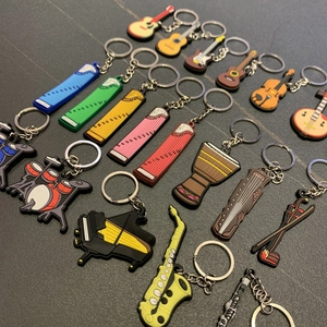Flat lay of colorful PVC musical instrument keychains on a dark textured surface