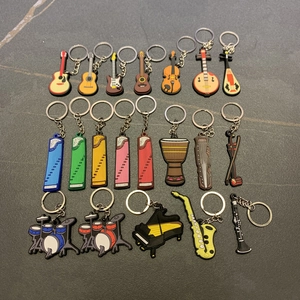 Detailed close-up of 20 assorted PVC musical instrument keychains on a stone surface