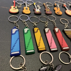 Detailed close-up of colorful PVC musical instrument keychains on a dark background