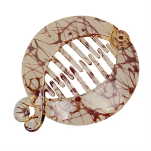 Detail view of round amber-toned banana hair clip with tortoiseshell pattern and teeth