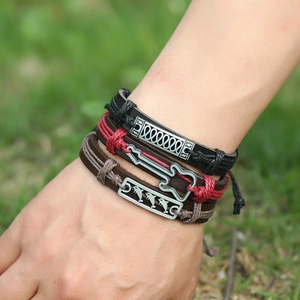 Three-piece set of woven leather bracelets with guitar and dolphin charms on wrist