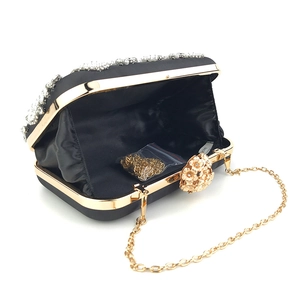 Detail of black satin evening clutch with rhinestones and gold chain strap
