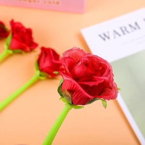 Detailed view of creative red rose gel pen with green stem on warm background