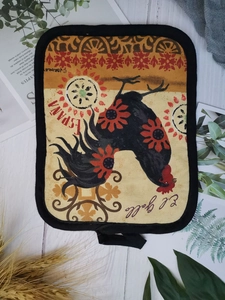 Thick cotton pot holder with rooster print and hanging loop on white wood background
