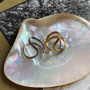 Close-up of gold and silver wavy irregular rings displayed in a pearl seashell