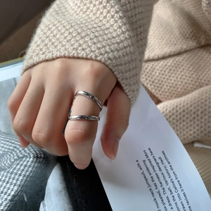 Close-up of minimalist silver double-line open ring on a model's hand with soft lighting