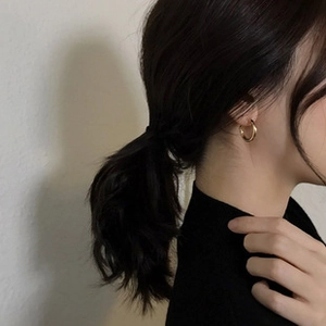 Primo piano di orecchini a cerchio ovali dorati minimalisti indossati da una modella di profilo