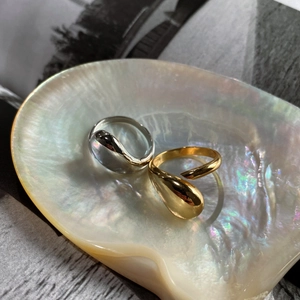 Irregular droplet open rings in gold and silver finish on an iridescent shell display