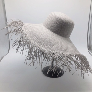 Detailed view of wide brim straw sun hat featuring trendy long frayed fringe edges