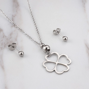 Minimalistische zilveren klaver ketting en oorknopjes set op wit marmeren achtergrond