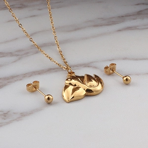 Polished gold stainless steel necklace set with organic pendant and ball studs on marble