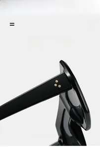 Detail of black acetate sunglasses showing three golden triangular studs on the temple hinge
