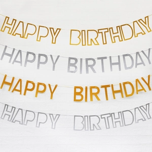 Glitter gold and silver Happy Birthday banners hanging on a white brick wall