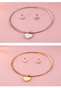 Close-up of polished heart pendant necklace and earring set in gold and silver finish