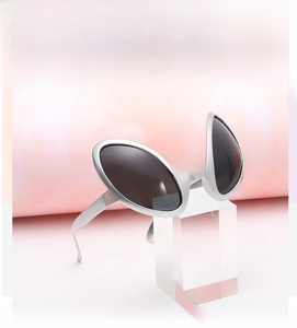 Detail of silver alien-shaped novelty party sunglasses on a pink gradient background
