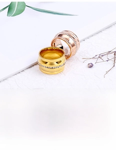 Macro detail of wide gold and rose gold rings with pavé set crystals on a textured surface