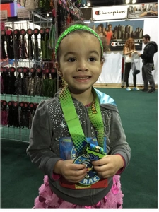 Detail of a young girl wearing a green sequin elastic headband with a runDisney medal