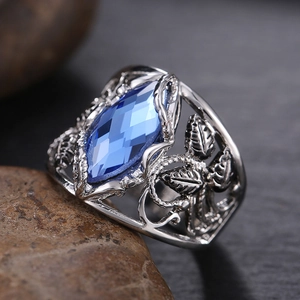 Macro detail of marquee-cut blue crystal ring with intricate leaf镂空 metalwork