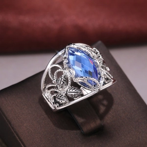 Vintage silver ring featuring a large marquise-cut blue crystal with ornate leaf engraving