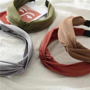 Flat lay of knotted fabric headbands in olive green, gray, brick red, and brown colors