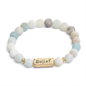 Detailed macro view of natural stone bead bracelet with Belief engraved metal plate