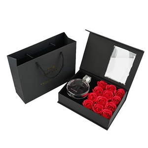 Top view of a black luxury gift box with nine red roses and a glass perfume bottle