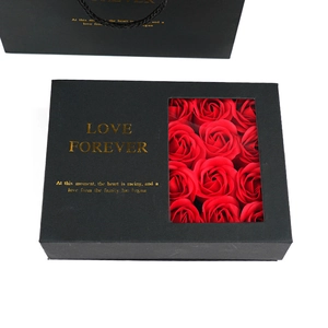 Close-up of black gift box with transparent window and 12 red soap roses and gold text