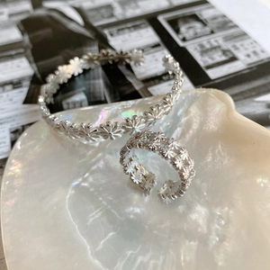 Detail of 925 sterling silver daisy ring and bracelet set on a shell with vintage vibe