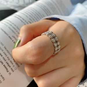 Macro detail of silver daisy floral relief ring on hand with aesthetic magazine background