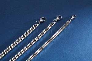 Close-up of three various widths of stainless steel chain bracelets with lobster clasps