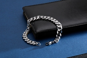 Close-up of silver Cuban link stainless steel bracelet on a black leather wallet