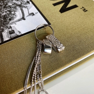 Close-up of 925 sterling silver tassel earrings with geometric charms on a yellow book