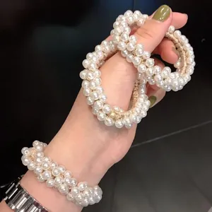 Elegant beaded pearl hair tie with gold elastic cord worn on wrist and hand