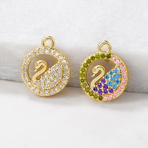 Detailed macro of golden swan pendants with white and colorful cubic zirconia inlay