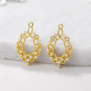 Macro shot of gold teardrop earring components with hollow design and inlaid cubic zirconia