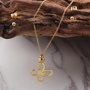 Detail of 18K gold plated butterfly necklace and sphere stud earrings on wood texture