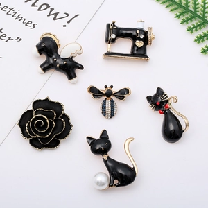 Set of six cute black enamel animal and plant brooches with gold plating on a white background