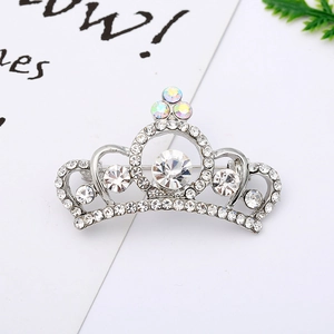 Macro shot of silver crown brooch with sparkling rhinestones and elegant hollow curves