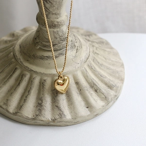Detailed close-up of 18K gold-plated heart pendant with elegant beaded edge texture