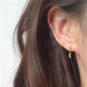 Macro shot of gold cross stud earrings with CZ stones on a female model's ear