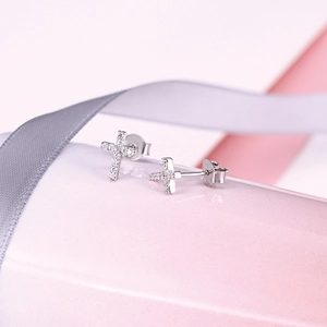 Macro shot of silver S925 cross earrings with sparkling diamonds on a soft background
