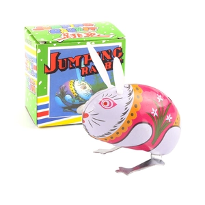Pink metal clockwork jumping rabbit toy with floral patterns on a white background