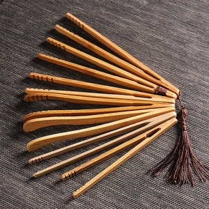 Eight bamboo tea clips with brown tassels and various heads on a dark textured background