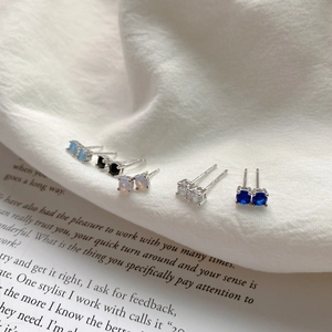 Set of five 925 silver stud earrings with colorful gemstones on white fabric